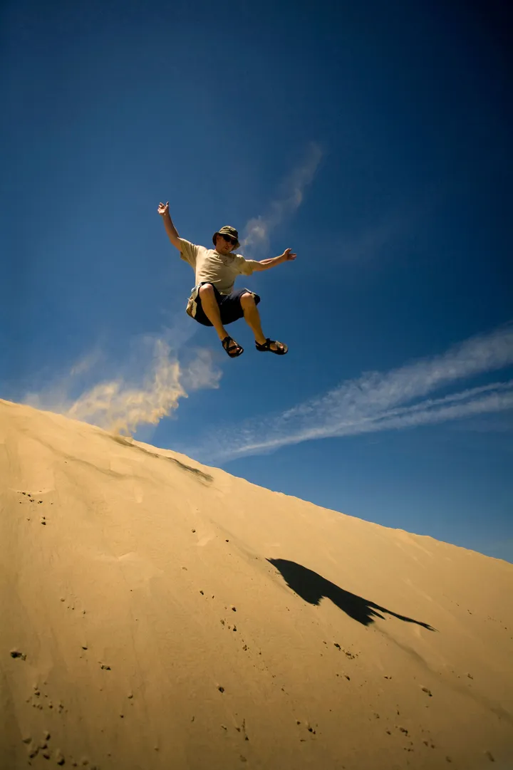 man jumping over great sand hills