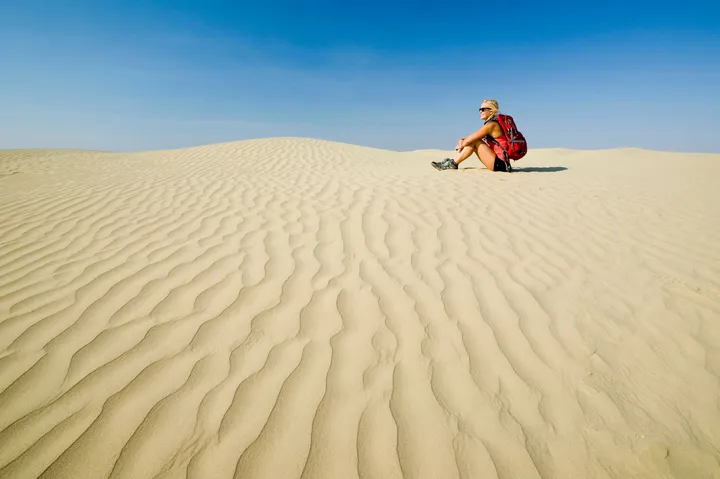 woman sitting on great sand hills dune